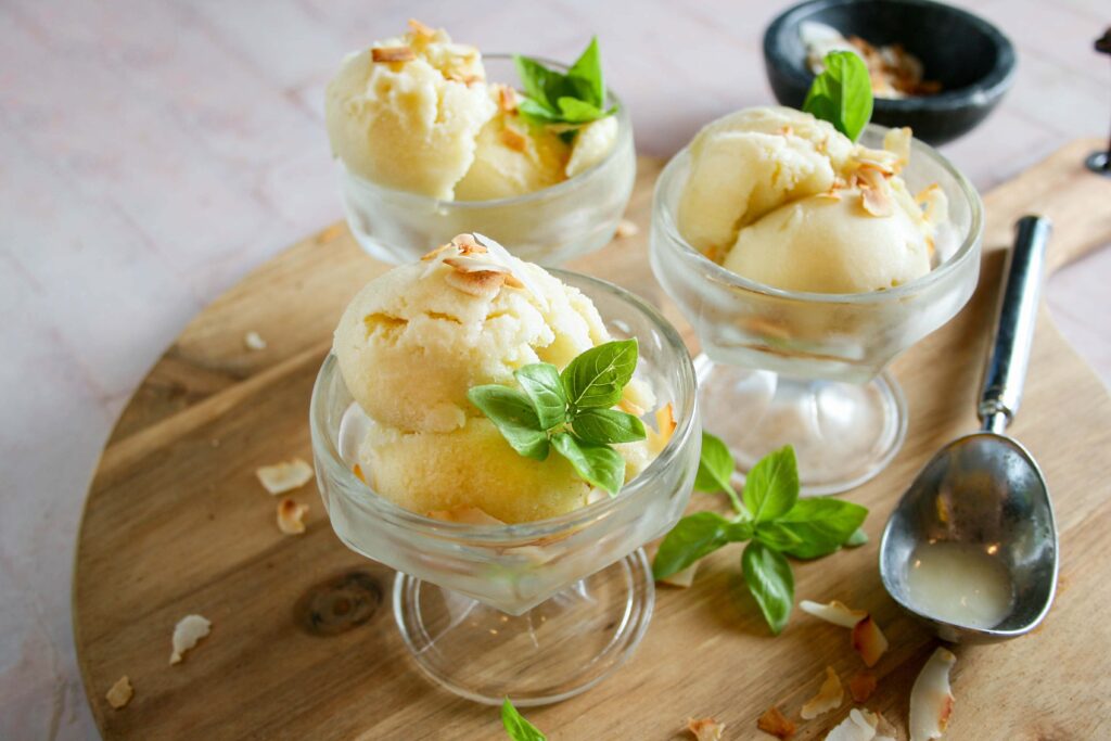 Coconut basil sorbet on a wooden platter in glass ice cream glasses